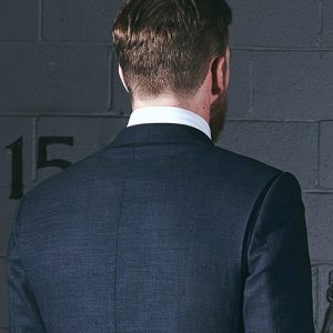 Product shot rear view of the Action Back Bi-Swing Back on a blue birdseye suit worn by a model in a shooting range